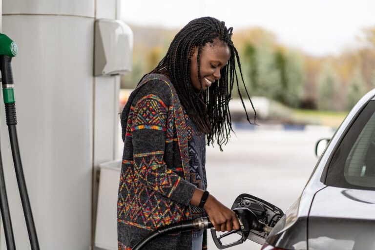 Person smiling while pumping fuel into vehicles gas tank. BZo2KYl