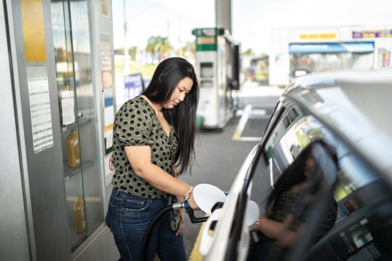 Woman refueling her car at a gas station 93tnEBk