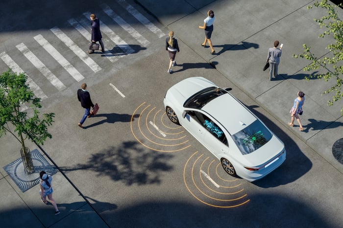 a digital render of a self driving car stopped at a cross walk surrounded by people