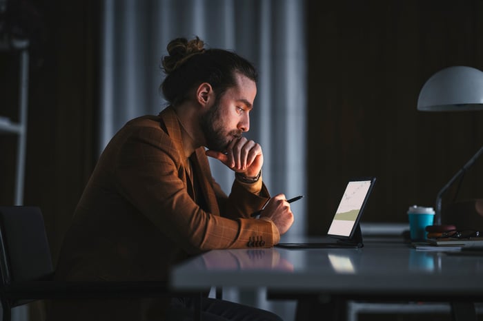thoughtful person looking at graphs on a tablet computer