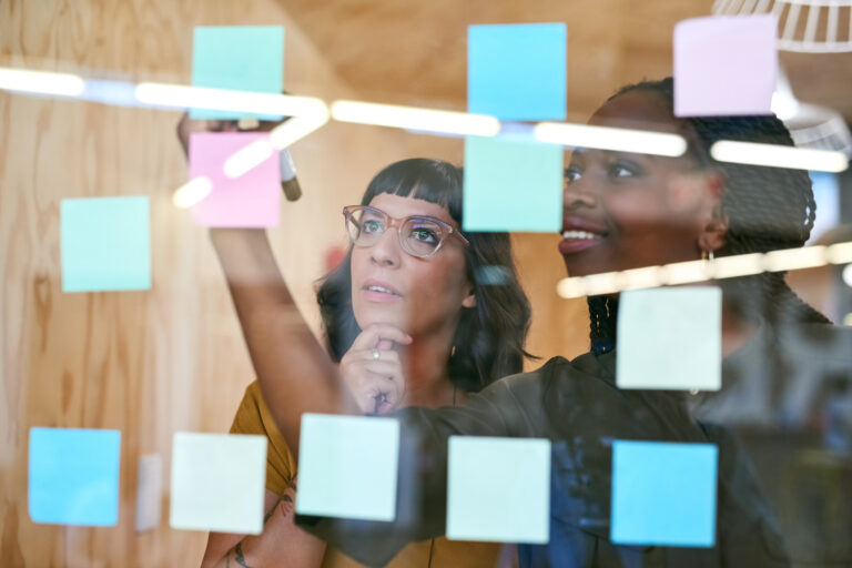 two investors put sticky notes on glass wall