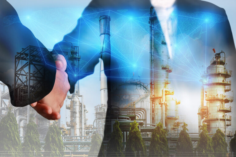 two people shaking hands with an energy facility in the background
