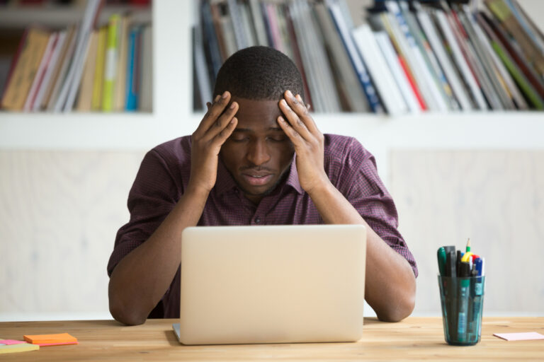 frustrated investor rubs head looks at computer