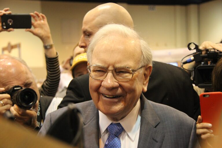 warren buffett smiling surrounded by cameras