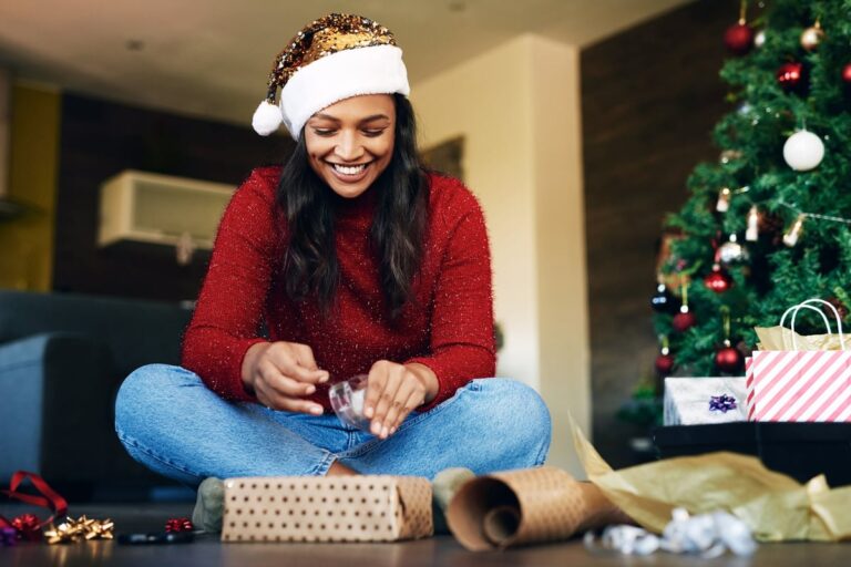 Woman wearing Santa hat wrapping gifts 4R8KFzT