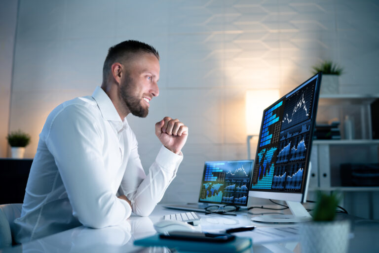 excited investor looks at financial charts on computer