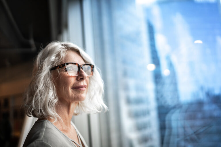 mature person looks optimstically out of a window