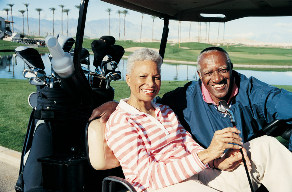 senior man and woman sitting in golf cart smiling poc