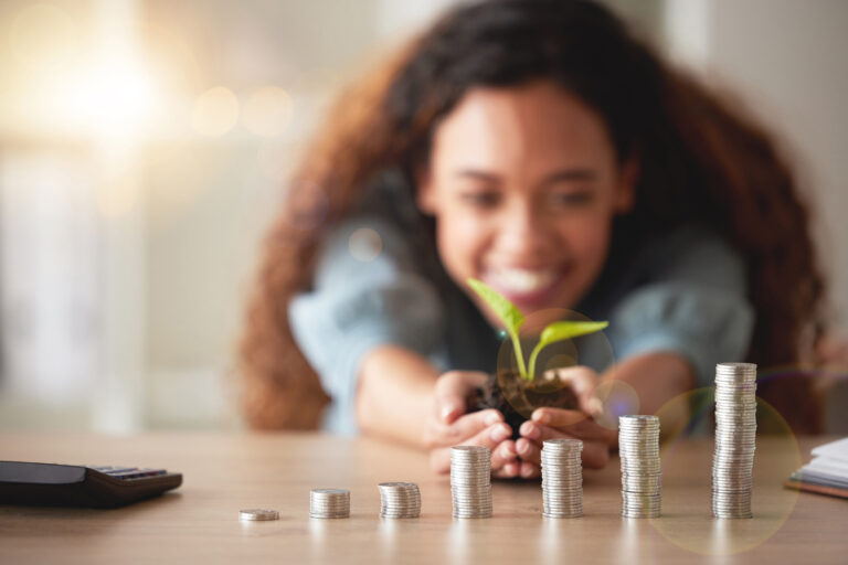 investor holds a sprouting plant behind coin stacks