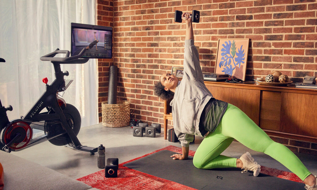 peloton bike in room while person is on floor excercising while looking at screen peloton