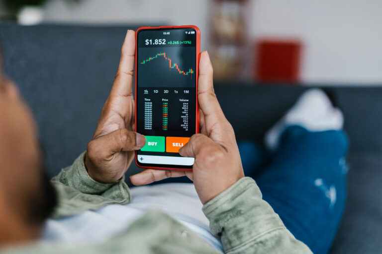 person laying on couch while looking at trading app on phone getty