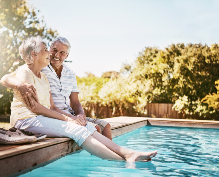 smiling seniors sitting by a pool