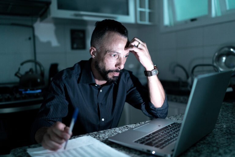 stressed investor sitting in dark at computer